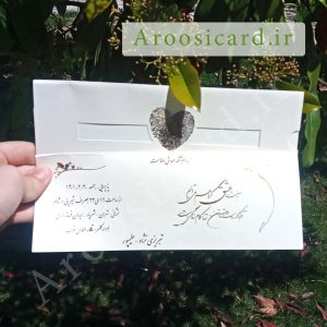 دستی که کارت عروسی ایلیا 395 با نوشته عربی روی آن در دست دارد.
